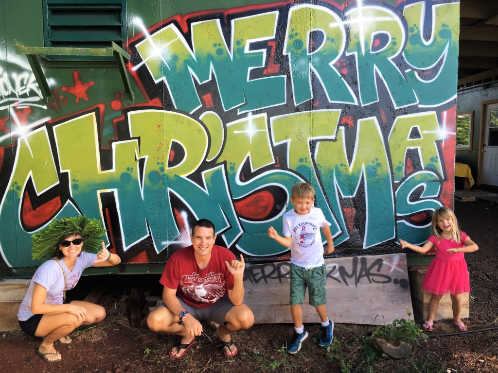 The Krueger kids dance in front of a grafiti Merry Christmas sign. Mari and Chris throw a shaka 