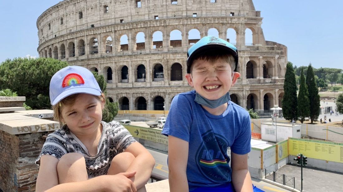 Two kids smiling in front of the Roman Coliseum