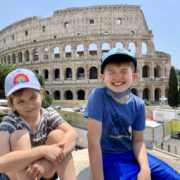 Two kids smiling in front of the Roman Coliseum
