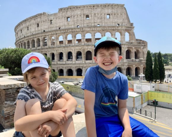 Two kids smiling in front of the Roman Coliseum